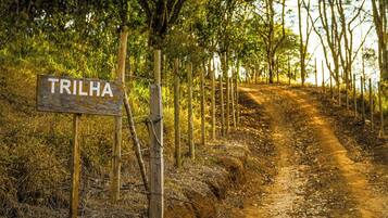 Un sendero de tierra con un letrero de madera que dice "TRILHA", rodeado de árboles.