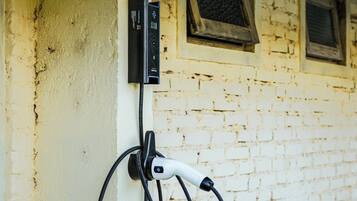 An electric vehicle charging station mounted on a wall with a brick wall background.