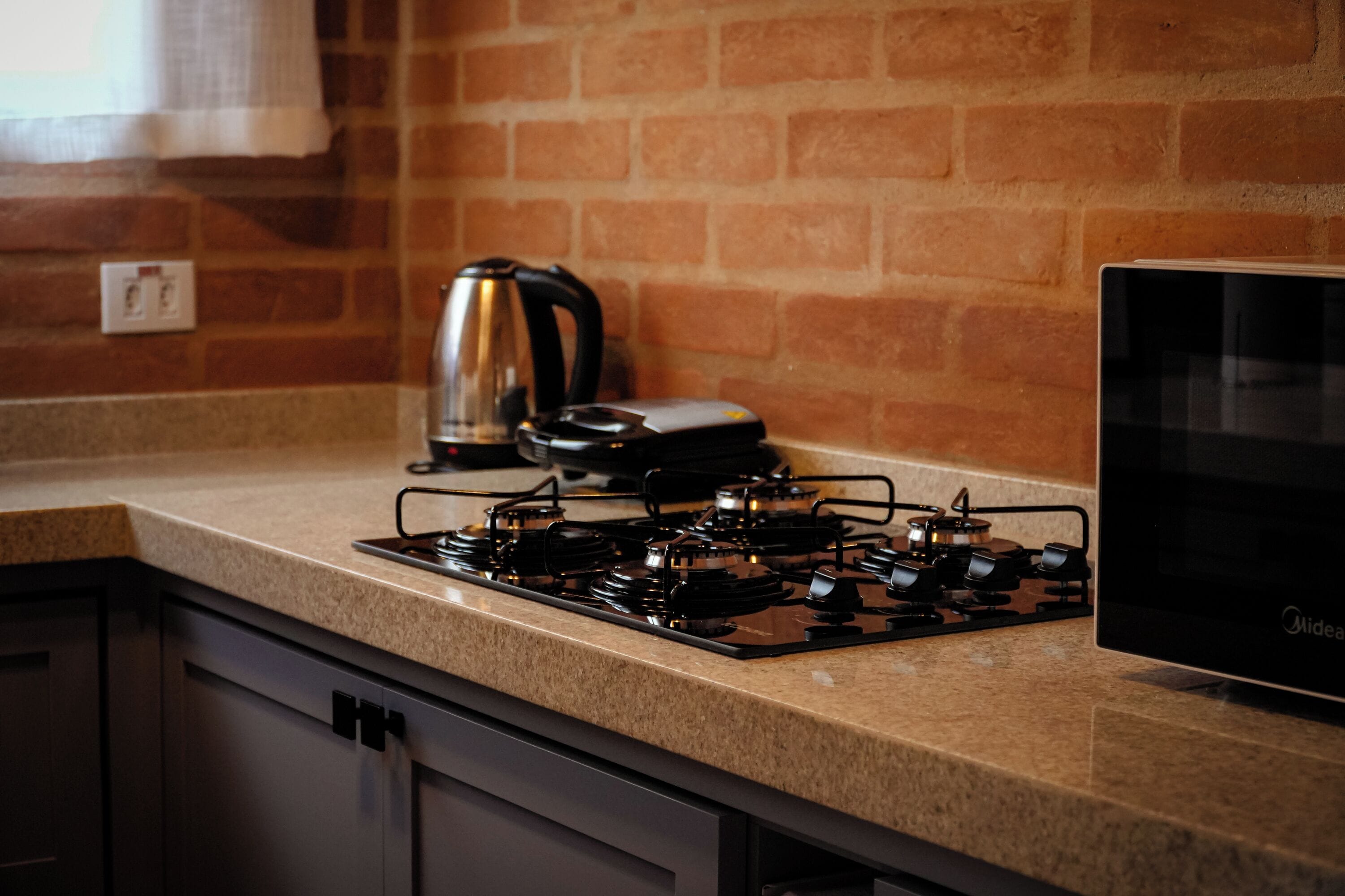 A kitchen with a gas stove, a kettle, and a microwave.