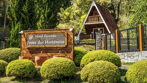 A wooden sign for Hotel Fazenda Fonte das Hortências with a triangular roof. - VELINN Hotel Fazenda Fonte das Hortênsias (Santo Antonio do Pinhal)