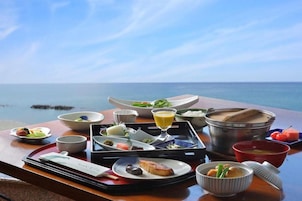 A table set with various dishes and a tray, overlooking the sea.