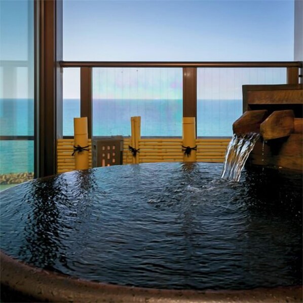 A hot tub with a view of the ocean through large windows. - Yusuitei Isagoya (Tsuruoka)