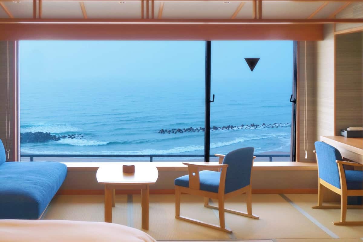 Una habitación con un amplio ventanal con vistas al mar, un sofá, una mesa y una silla.
