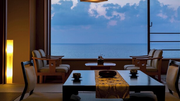 A dining area with a view of the sea, a table with a patterned tablecloth, and chairs. - Yusuitei Isagoya (Tsuruoka)