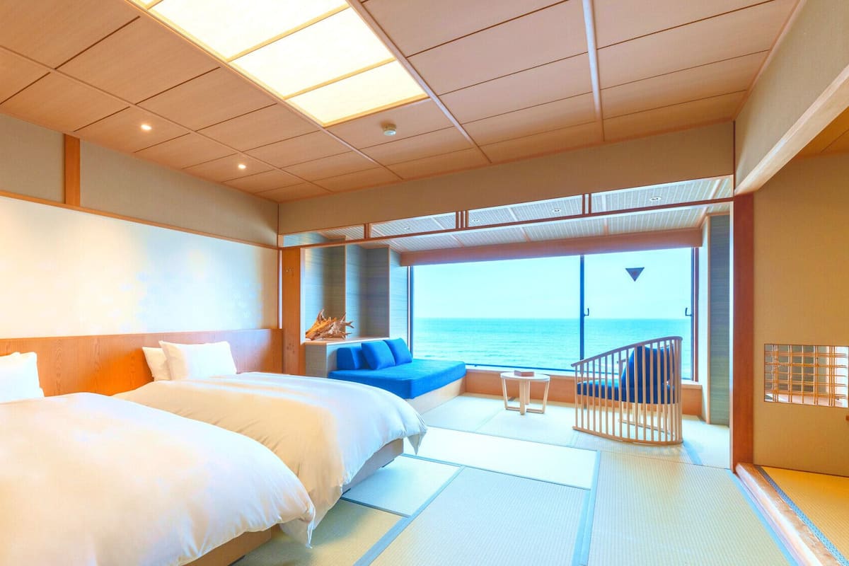 A hotel room with a large bed, a seating area with a view of the sea, and a balcony.