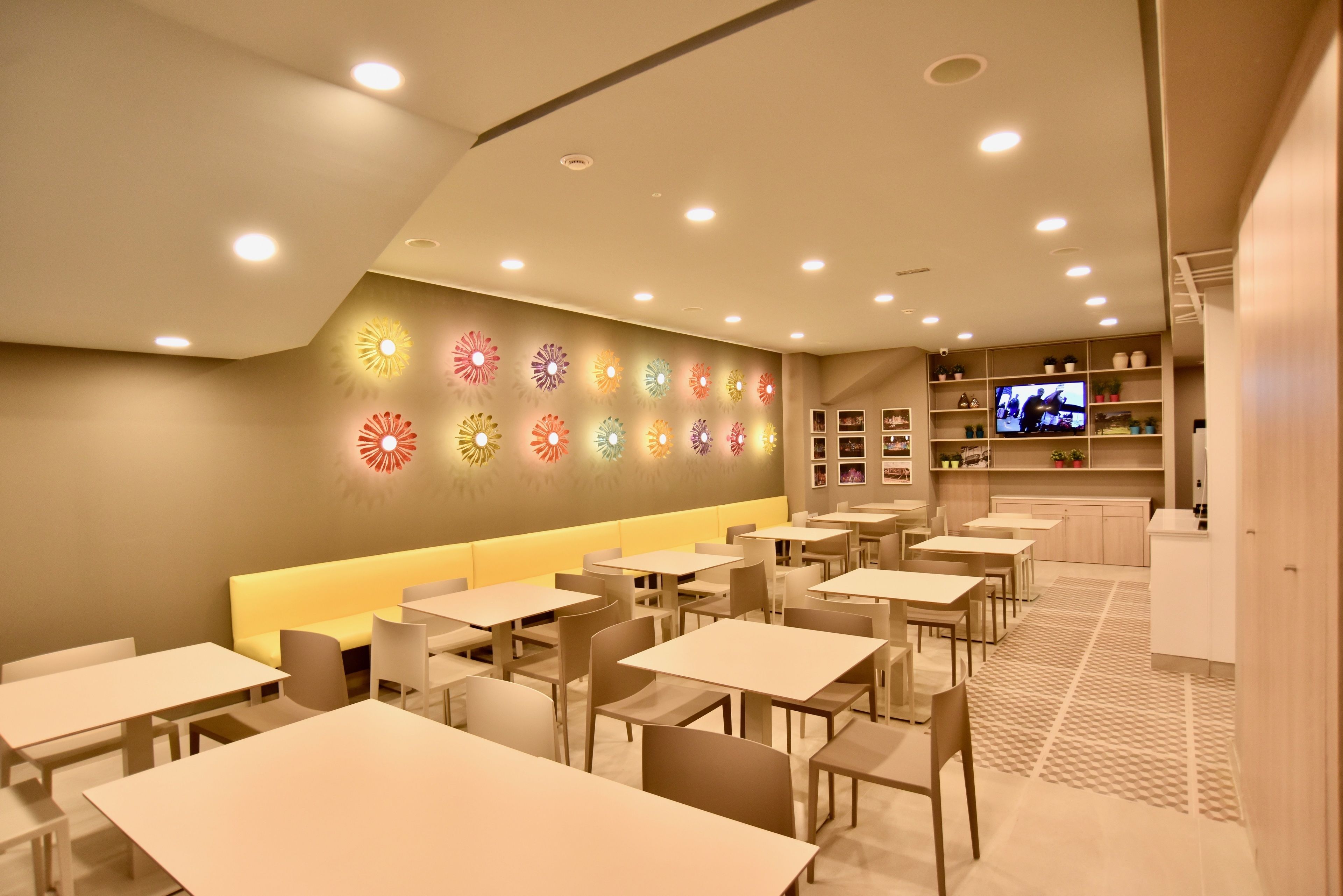 Un restaurant moderne doté de nombreuses tables et d’un long banc servant de coin salon.