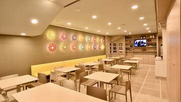 Un restaurant moderne doté de nombreuses tables et d’un long banc servant de coin salon.