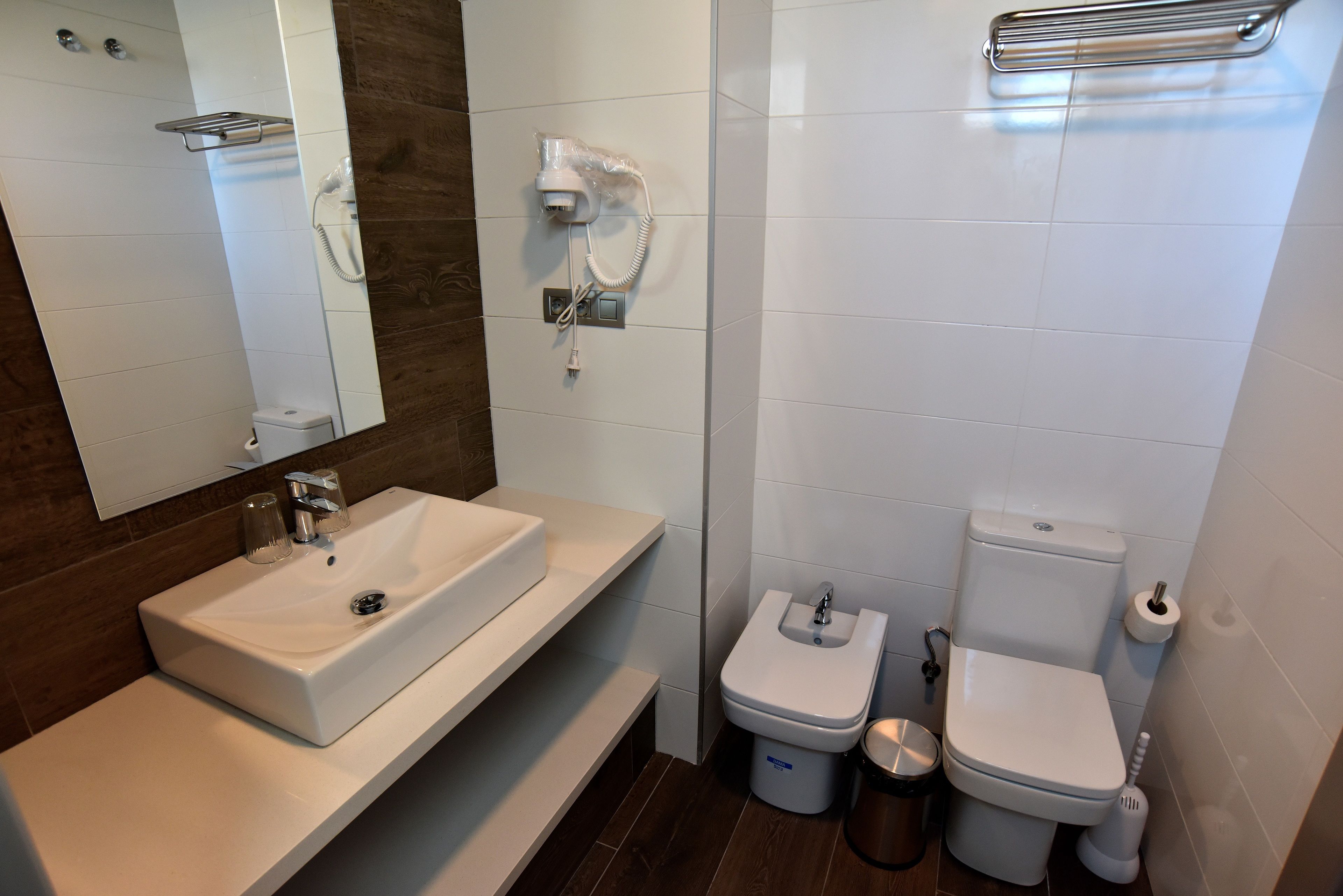 Un baño moderno con un espejo grande, un lavamanos, un inodoro y un bidé.