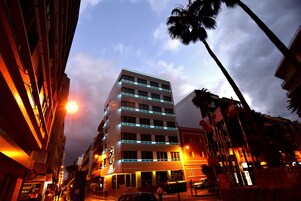 A multi-story hotel with a modern design, featuring illuminated balconies and a prominent entrance.