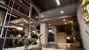 A modern interior with a staircase, metal shelving with plants, and a well-lit elevator area. - TC Hotel Doña Luisa (Las Palmas de Gran Canaria)