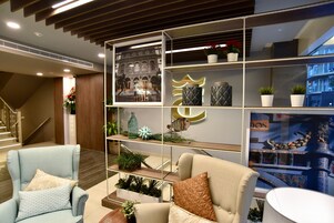 A modern interior with a staircase, two armchairs, a bookshelf, and decorative items.