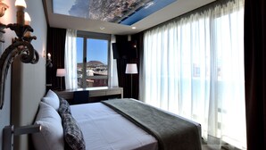 A hotel room with a large bed, a cityscape view through the skylight, a desk, and a window with curtains. - TC Hotel Doña Luisa (Las Palmas de Gran Canaria)