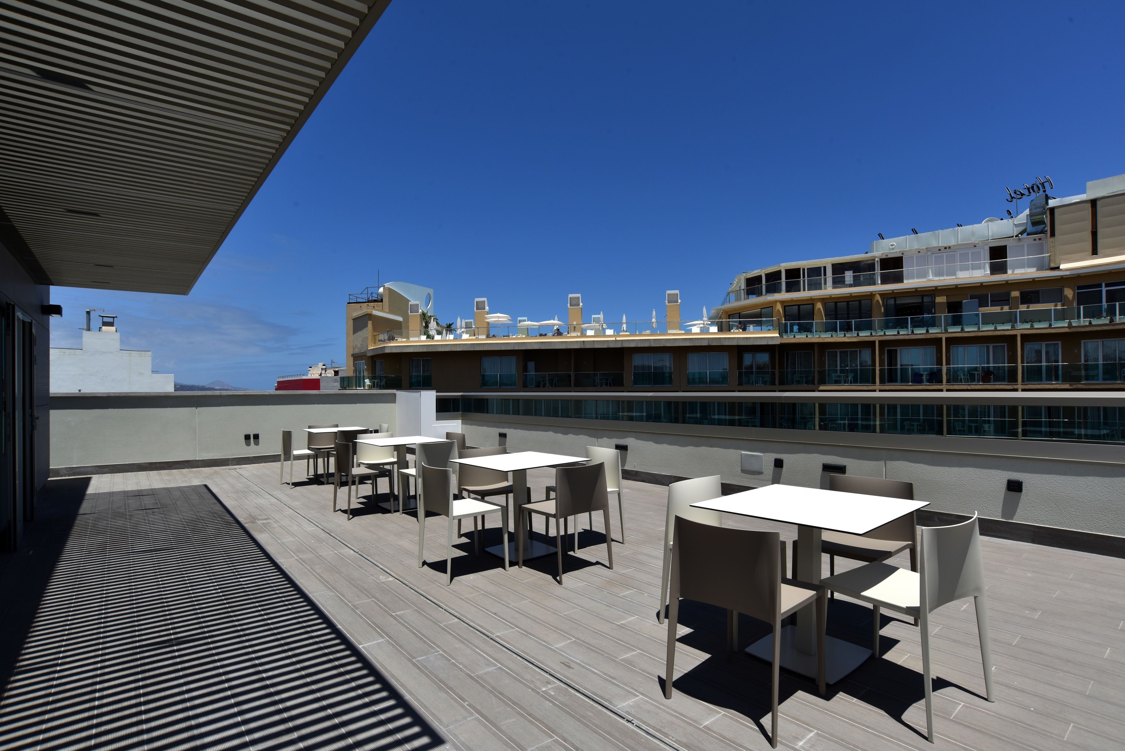 Une terrasse sur le toit, dotée d’un espace extérieur aménagé et offrant une vue sur un bâtiment moderne.