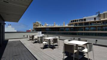 Une terrasse sur le toit, dotée d’un espace extérieur aménagé et offrant une vue sur un bâtiment moderne.