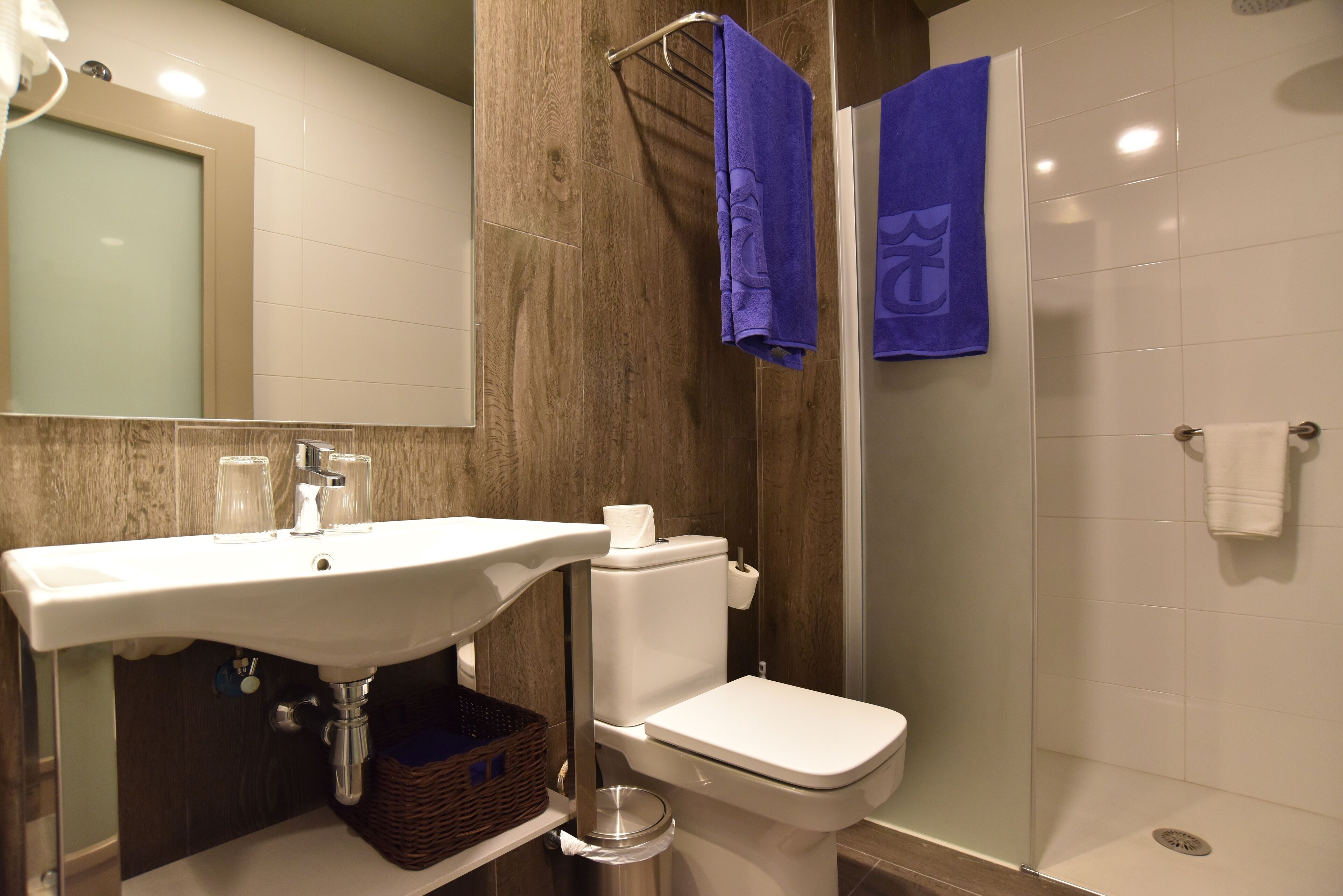 Ein Badezimmer mit weißem Waschbecken, WC und Duschkabine aus Glas.