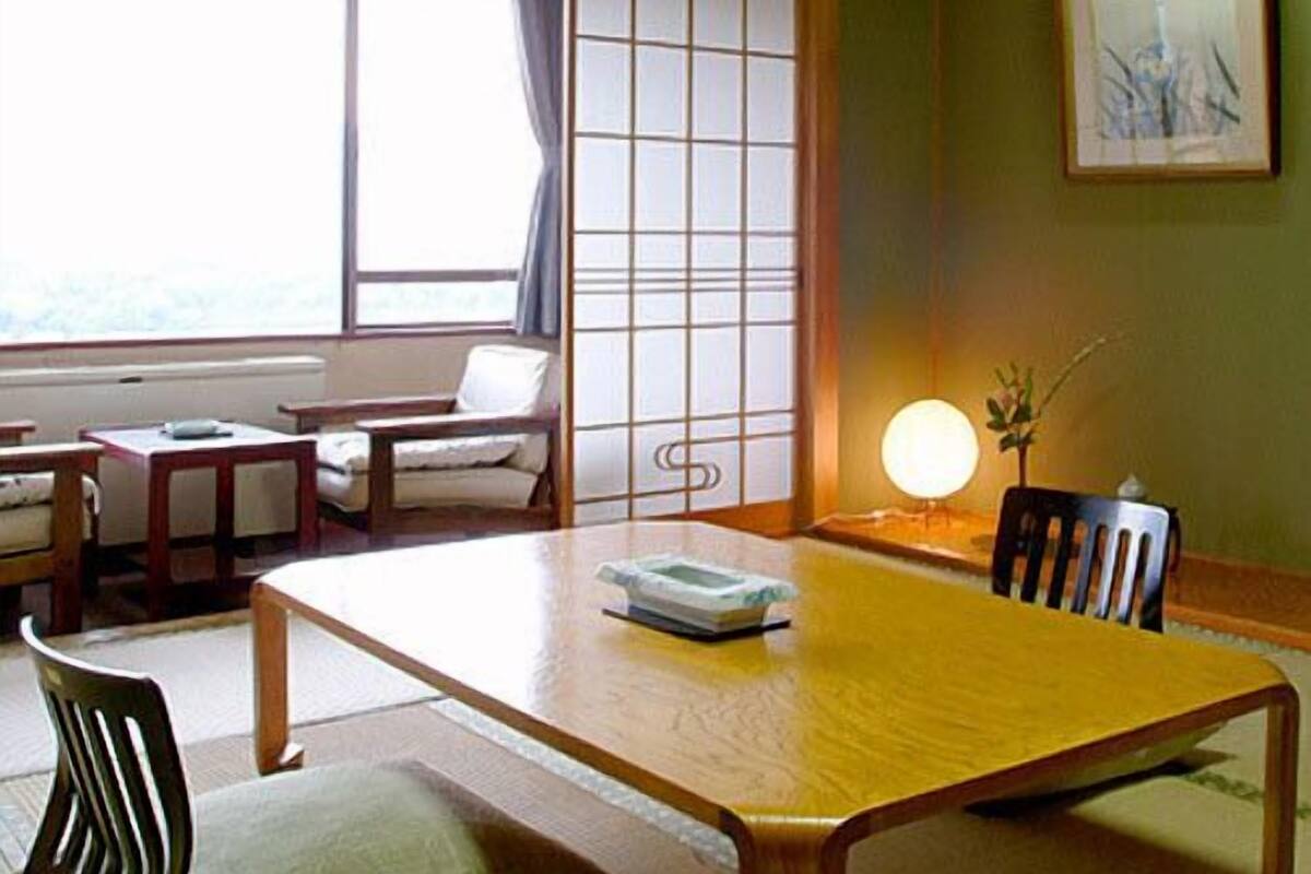 Une pièce de style japonais traditionnel, avec un sol recouvert de tatamis, une basse table en bois, un canapé et un paravent en papier de riz (shoji).
