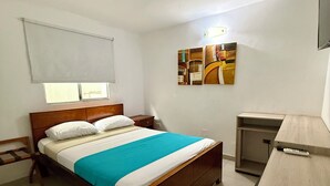 A bedroom with a bed, a desk, and a TV. - Hotel Monterrey (Barranquilla)