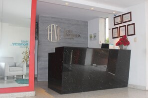 Ein moderner Hotelrezeptionstresen mit einem Rahmen um das Willkommen-Schild und einem Blumentopf.