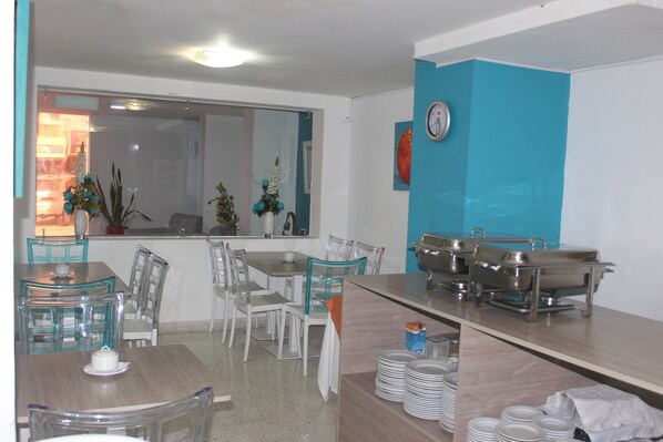 Comedor con un ventanal grande, un reloj en la pared y servicio de buffet.