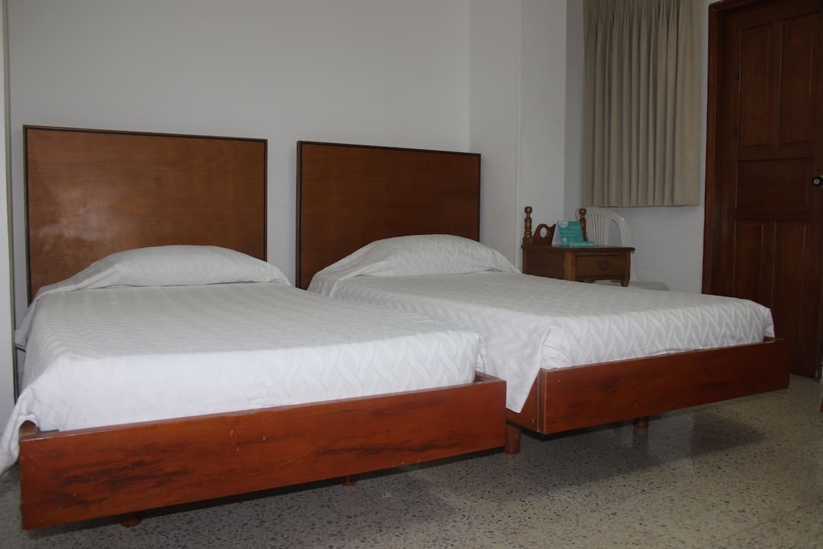 A room with two wooden beds, a nightstand, and a door.