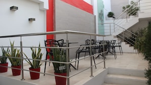 A staircase with metal railings, potted plants, and outdoor seating with chairs and tables. - Hotel Monterrey (Barranquilla)