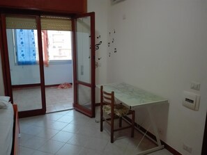 A room with a dining table, a chair, a map on the table, and a door leading outside. - Deltamartini (Trapani)