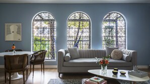 A living room with a grey sofa, a coffee table, and a dining area with a round table and chairs. - Casa Legado (Bogotá)
