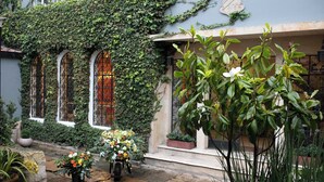A courtyard with a stone pathway, potted plants, and a motorized cart with flowers. - Casa Legado (Bogotá)