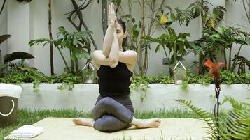 Guests can practice yoga in a serene outdoor space surrounded by lush greenery and a peaceful atmosphere.