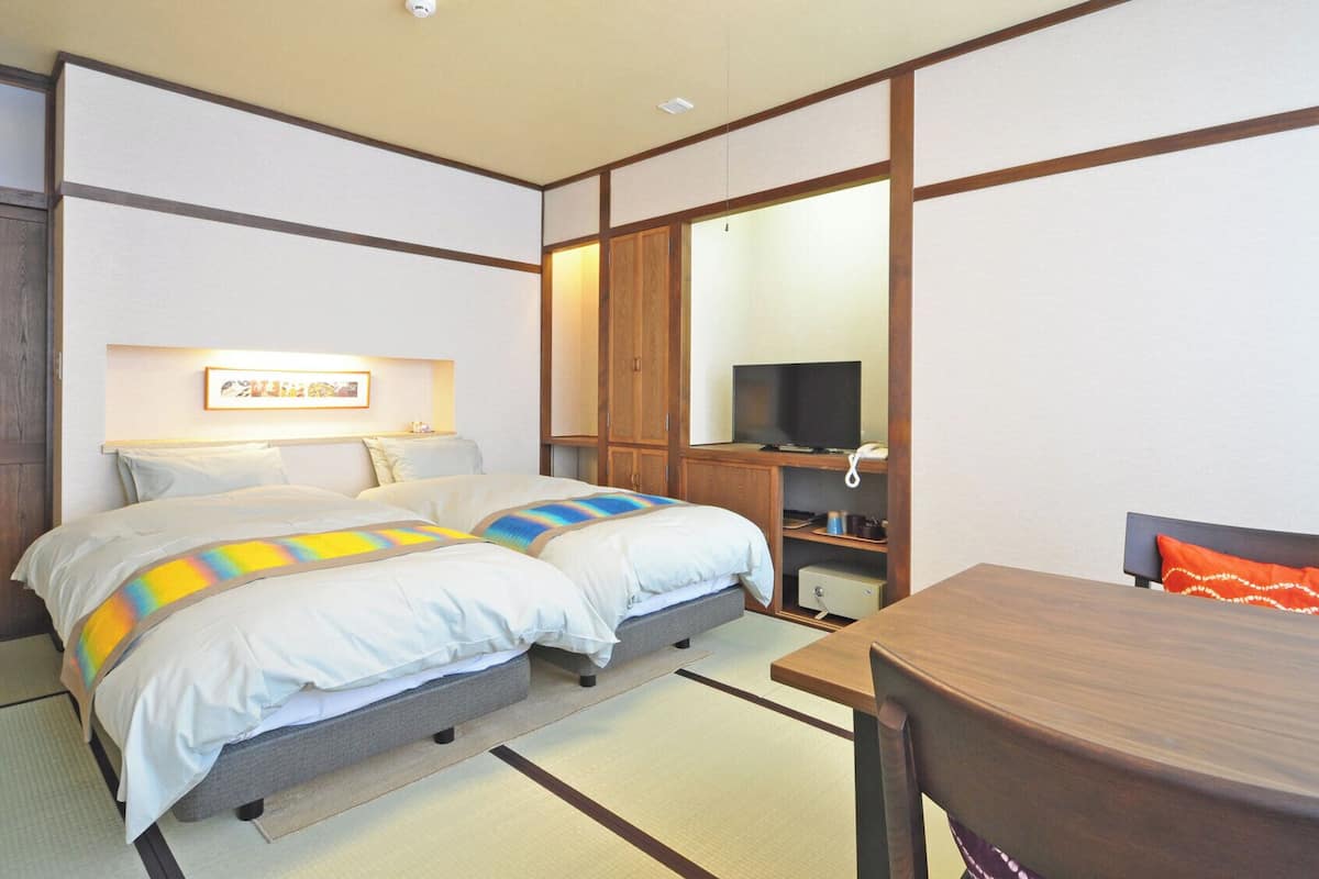 Una habitación de hotel con cama, escritorio, silla, televisor y armario.