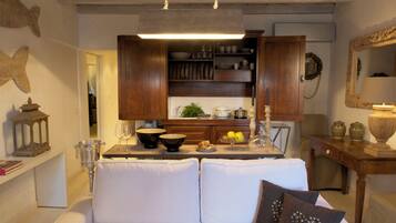 Una sala de estar acogedora con un sofá blanco, una cocina con armarios de madera y una mesa de comedor.