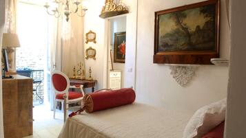 A bedroom with a bed, a chair, a desk, and a painting on the wall.