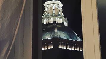 A close-up of a building's ornate tower with a dome and spire, illuminated at night.
