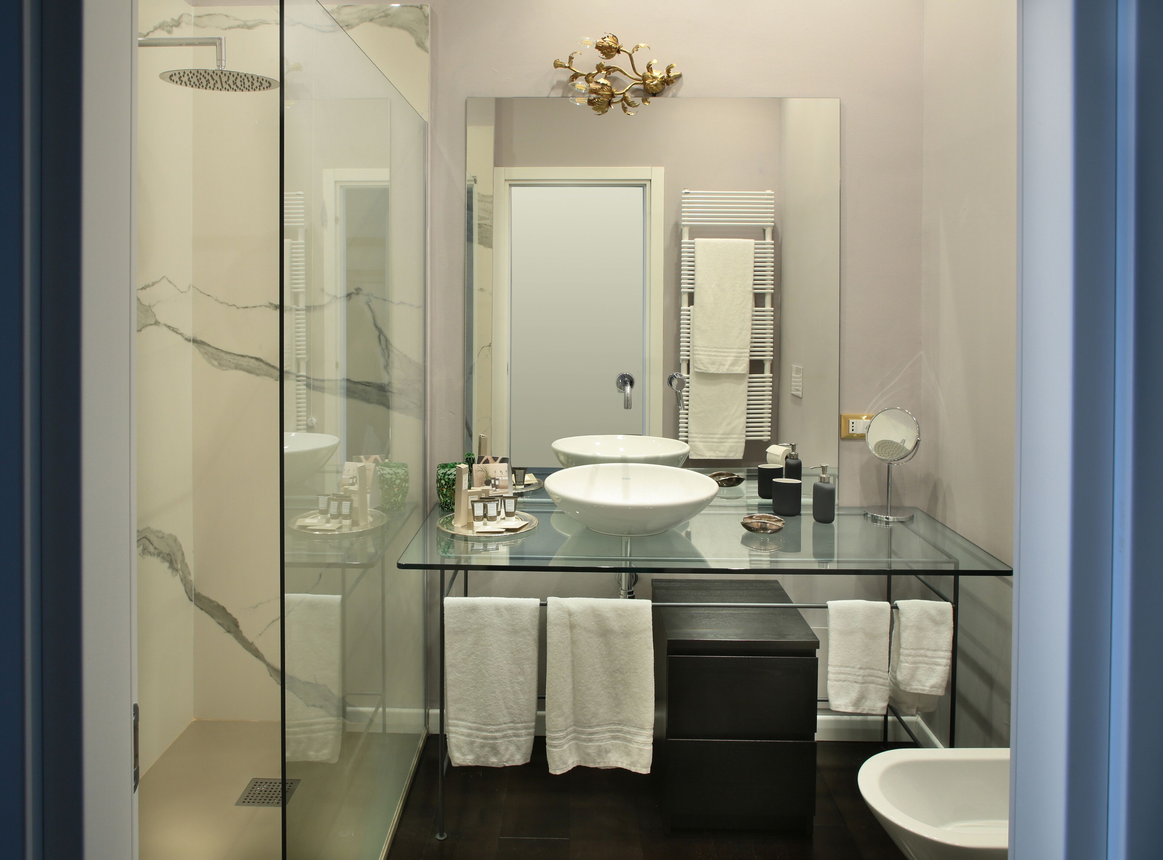 Une salle de bain moderne avec une douche à l’italienne, un grand miroir et un meuble-lavabo noir avec un vasque blanche.