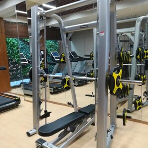 A gym with exercise equipment, treadmills, and weightlifting stations. - Rongjiang Hotel (Jieyang)