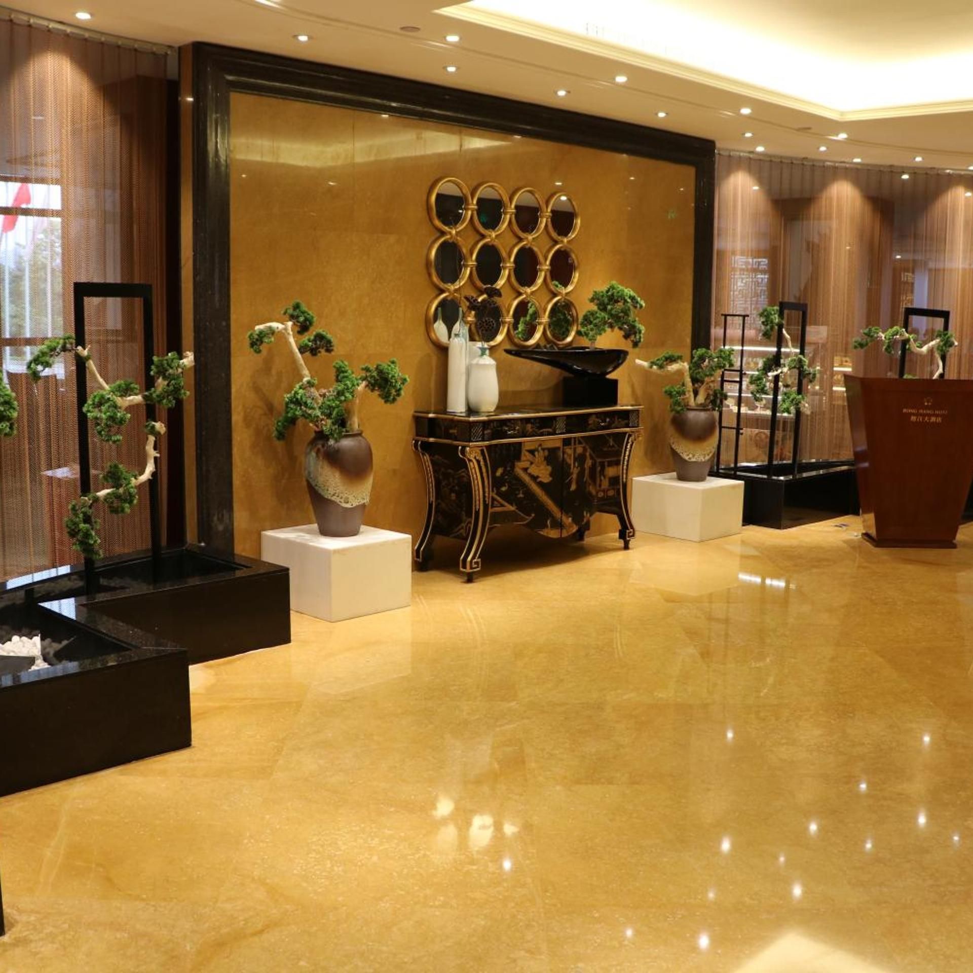 A lobby with a polished floor, a reception desk, and potted plants.