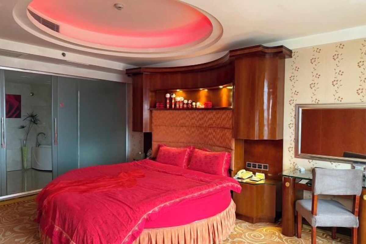 A bedroom with a large bed, a desk, and a television.