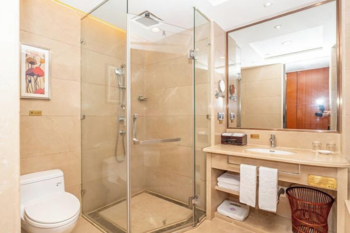 A modern bathroom with a glass-enclosed shower, a white toilet, a vanity with a mirror, and a towel rack.