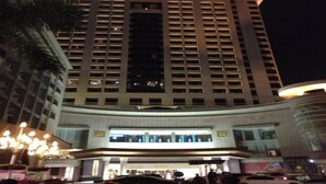 A high-rise hotel with a prominent entrance, multiple floors, and a well-lit facade. - Rongjiang Hotel (Jieyang)