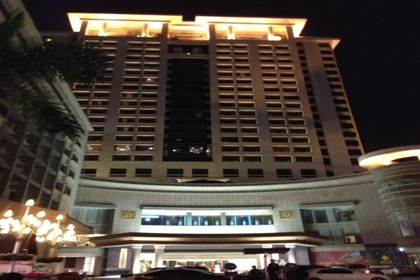 Un hotel moderno de gran altura con una entrada destacada, varios pisos y una fachada bien iluminada.