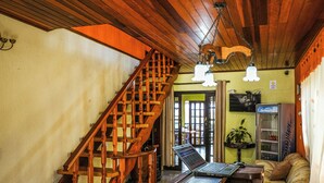 Eine Holztreppe, ein Laptop auf einem Tisch, eine Couch und ein Verkaufsautomat in einem Raum mit Holzbalkendecken und -wänden.
