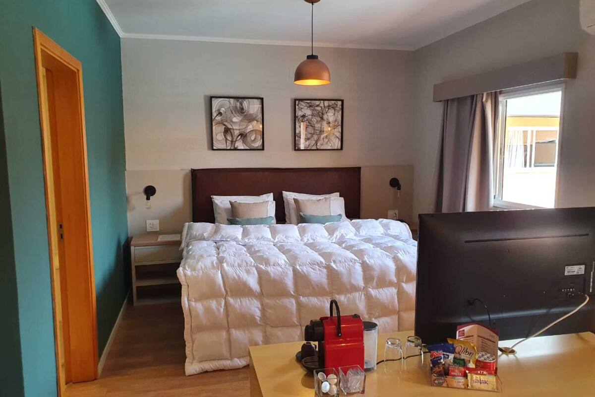 Une chambre d’hôtel équipée d’un lit, d’une télévision, d’un bureau avec des collations et de deux œuvres d’art murales.
