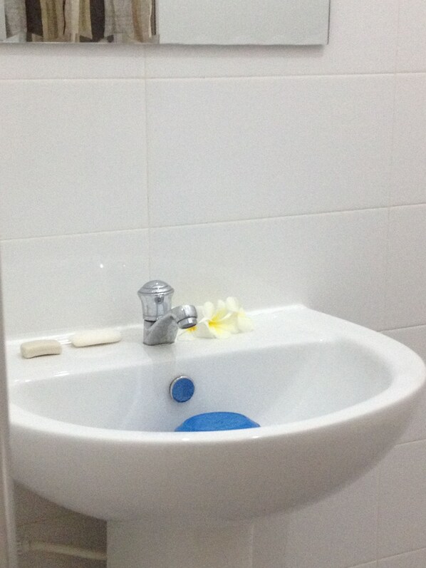 A white bathroom sink with a silver faucet, a blue drain cover, and two soap bars. - Manik Home Stay (Negombo)
