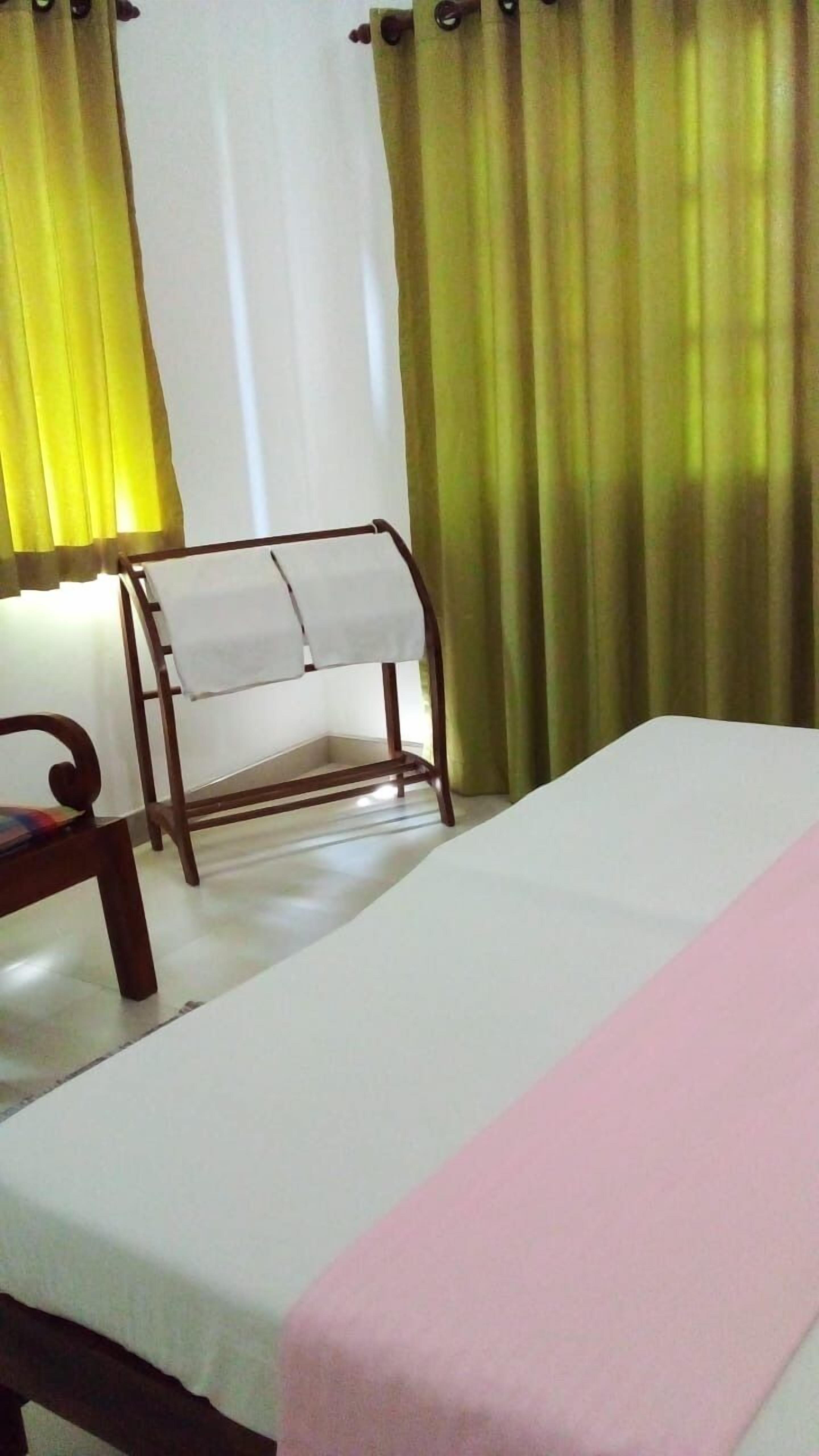 A hotel room with a bed, a wooden chair, and a small table.