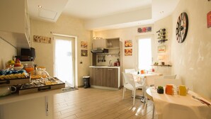 Una cocina luminosa con armarios de madera, un comedor con mesa y sillas, y un bufé de desayuno con diferentes alimentos.
