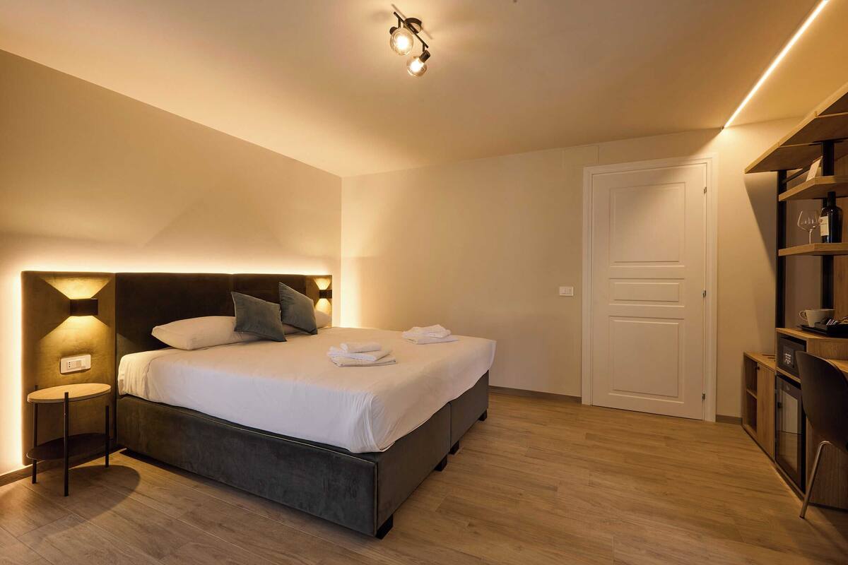 A modern bedroom with a bed, bedside tables, a wardrobe, and a door.