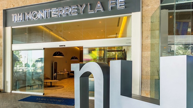 A hotel entrance with a modern design, featuring a large glass facade and a prominent 'THIMONTERREYLA FE' sign. - NH Monterrey La Fe (San Nicolas de los Garza)