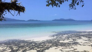 A beach with clear turquoise water, white sand, and distant mountains. - Yuyu Golden Beach (Ko Chang)