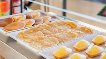 A buffet with various breakfast items including pancakes, waffles, and pastries.