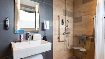 Un baño moderno con un espejo grande, un lavabo, una ducha con cabezal de ducha manual y un perchero para toallas.